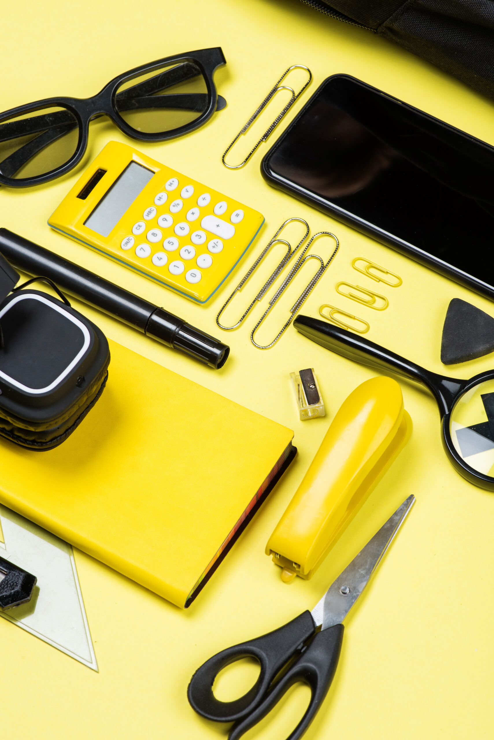 Close-up view of calculator, smartphone and school supplies on yellow